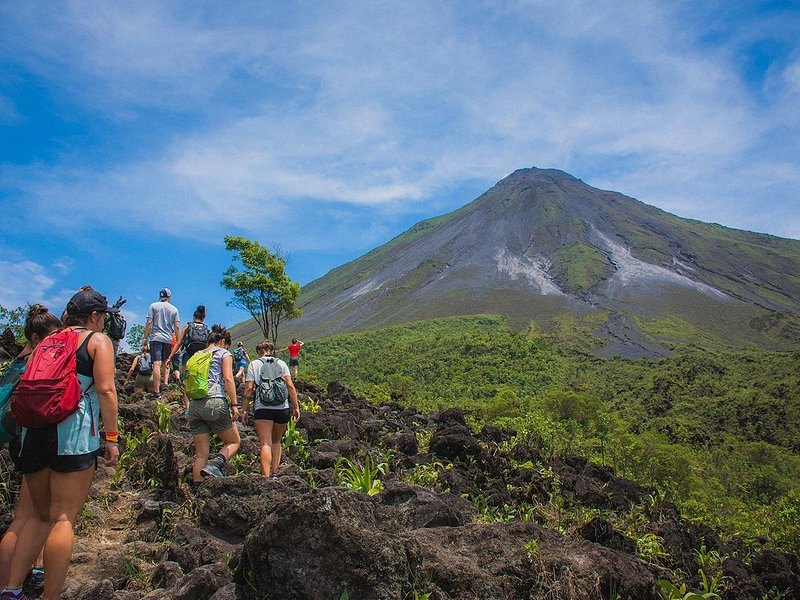 Walkers crossing the old lava field on the trail below Arenal Volcano